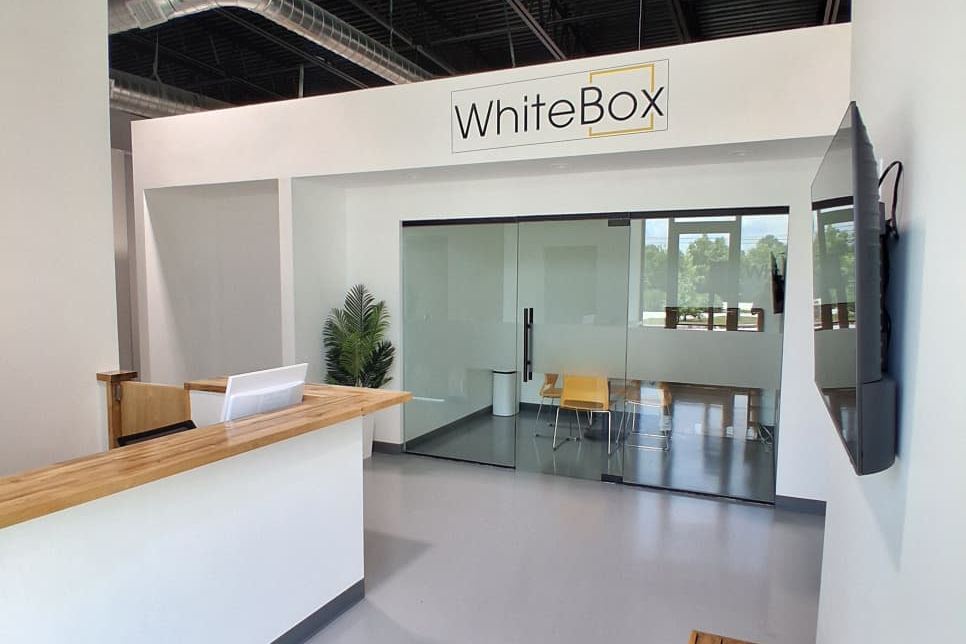 The WhiteBox lobby, with a wood-topped front desk and a glass-walled conference room