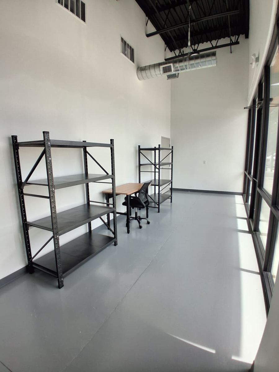 A WhiteBox unit with black steel shelving, a desk and chair, and floor-to-ceiling windows